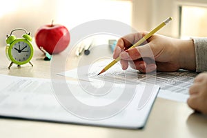 Female student hands testing in exercise and taking fill in exam paper sheet with pencil at school test