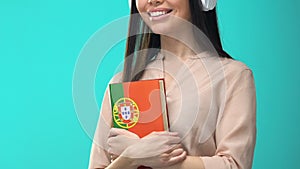 Female student headphones holding Portuguese book online seminar, knowledge