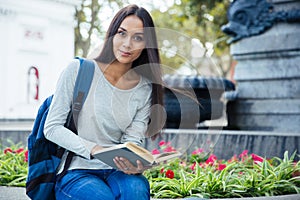 Female student holding book and looking at camera