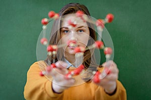 Female student holding molecular structure model. Science class.