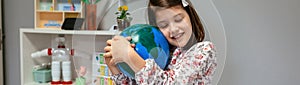 Female student hugging a handmade globe world at ecology classroom