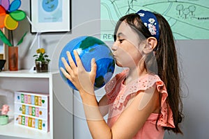 Female student kissing a handmade globe world at ecology classroom