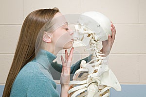 Female student kissing a human skeleton