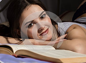 Female student laying in bed and read book, girl dreaming about life