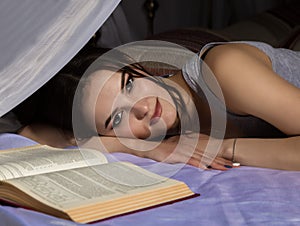 Female student laying in bed and read book, girl dreaming about life