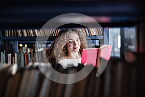 Female student in library, looking for books, preparing for final exam.