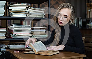 Female student at the library, she is sitting at desk and studying, education and self improvement concept