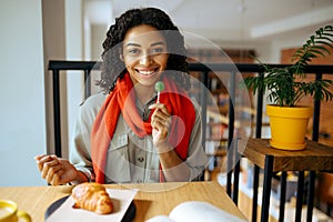 Female student with lollipop at the table in cafe