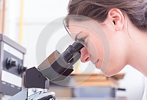 Female student looking into the microscope