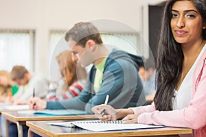 Female student with others writing notes in classroom