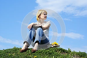 Female student outdoor on gren grass with books