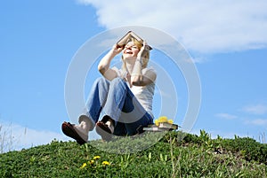 Female student outdoor on gren grass with books