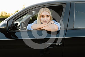 Female student poses in car, driving school