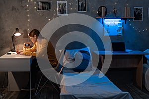 Female student preparing for university exams at dormitory room at late night