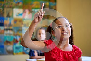 Female Student Raising Hand During Test In Class At School photo