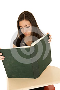 Female student reading a large book with a confused expression