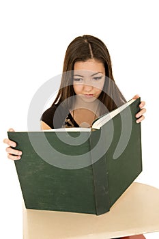 Female student reading a large book at a school desk
