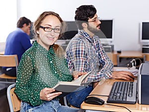 Female student reading textbook in computer class