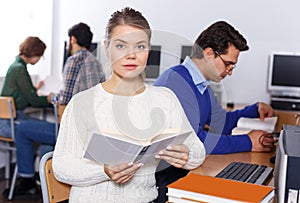 female student reading textbook while studying