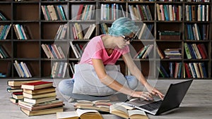 Female student researching with books and laptop