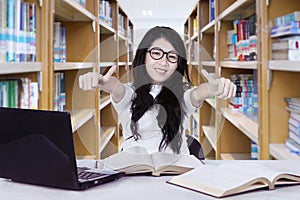 Female student showing thumbs up in the library