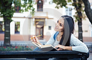 Female student sitting on the bench with book