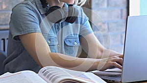Female student sitting brown table typing keyboard opened laptop, textbooks