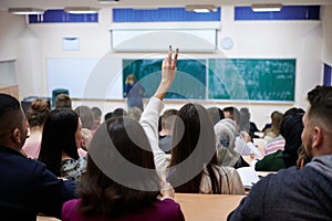 female student sitting in the class and raising hand up