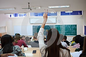 female student sitting in the class and raising hand up