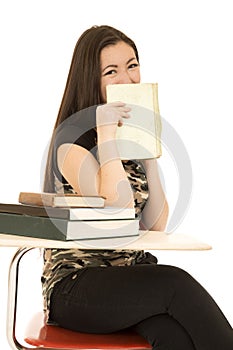 Female student sitting at her desk hiding her face with book sm