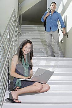 Female Student Sitting While Man Walking Down Stairs