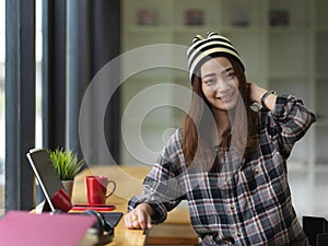 Female student smiling and looking into camera while doing assignment in cafe