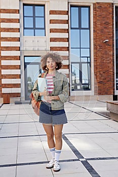 Female student standing outdoors in modern college campus with backpack