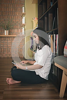 Female student study in school library sitting against bookshelf