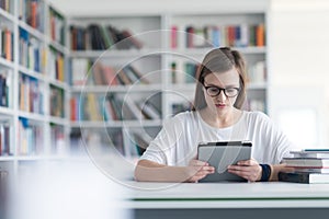 Female student study in school library, using tablet