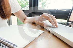 Female student taking notes from a book at library. Young asian woman sitting at table doing assignments in college library.