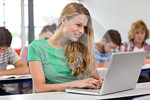 Female student using laptop in classroom