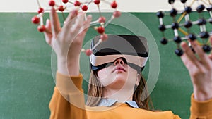 Female student wearing virtual reality glasses, holding molecular structure model. Science class, Education, VR, New Technologies.
