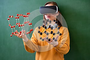 Female student wearing virtual reality glasses, holding molecular structure model. Science class, Education, VR, New Technologies.