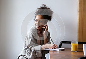 Female student working at home and talking on mobile phone
