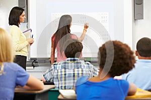 Female Student Writing Answer On Whiteboard