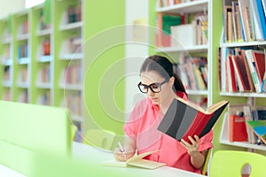 Female Student Writing an Essay Assignment in School Library