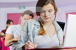 female student writing notes in class