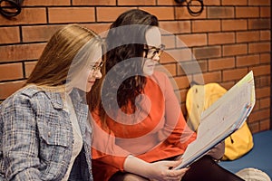 Female students sit in the corridor of the university / university dormitory and teach homework, lectures. The girl explains to