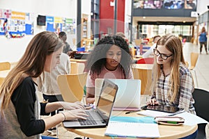 Female Students Working In Communal Area Of Busy College Campus