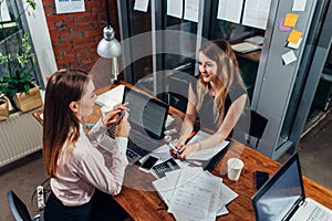 Female students working on school assignment using laptops sitting at desk in a study room