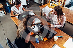 Female students working on school assignment using laptops sitting at desk in a study room