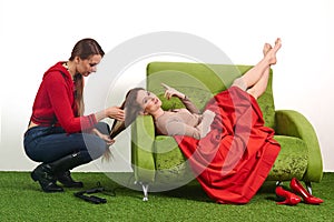 Female stylist straightens the hairstyle of the model while she is resting in between shoots