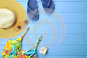 Female summer beach accessories hat, swimsuit, sunscreen, sunglasses, hat, flip flops and earphones flat lay, top view, copy space