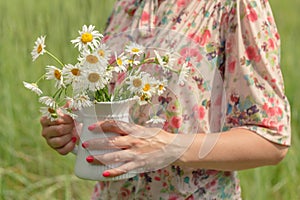Female in summer park hold bouquet of daisy flowers